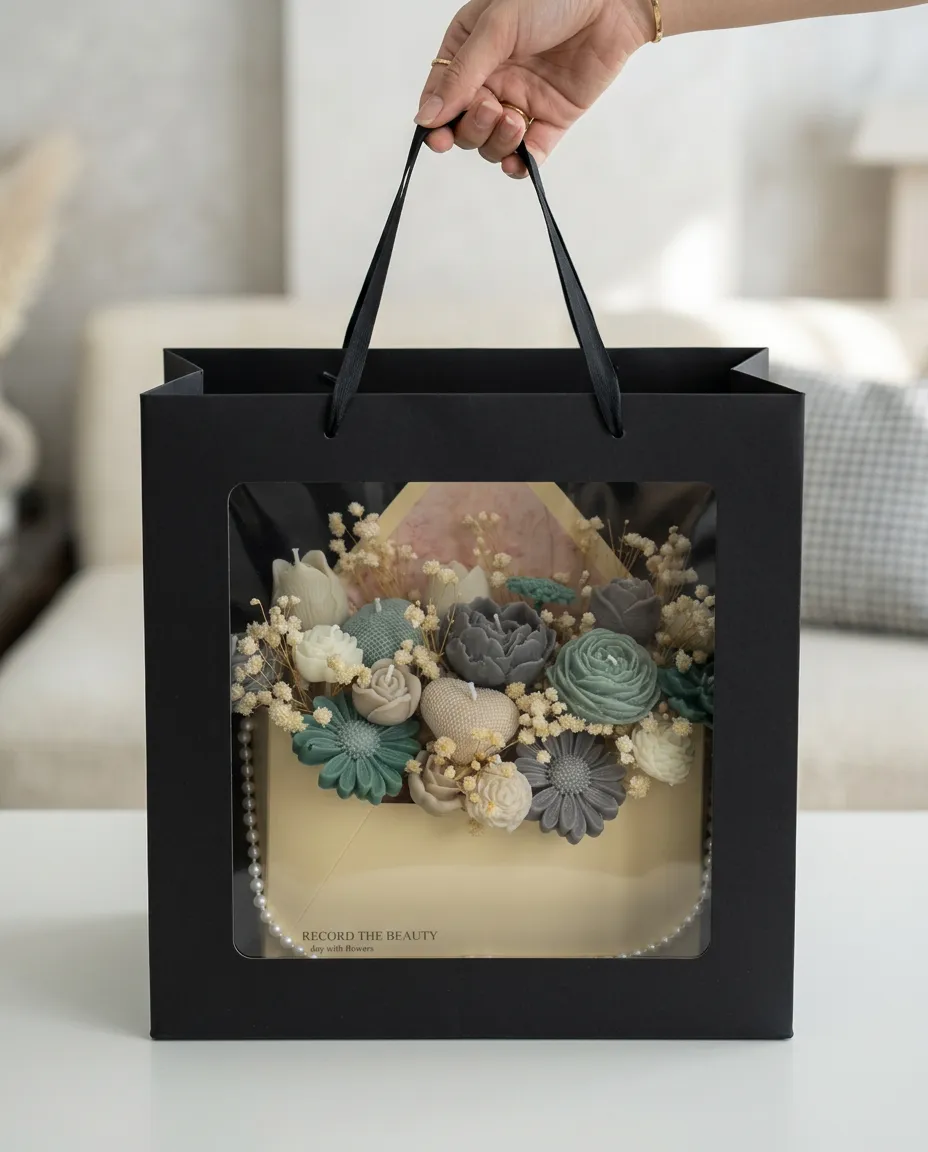 L'enveloppe sauge & ardoise présentée dans un sac cadeau noir, dans un salon lumineux.